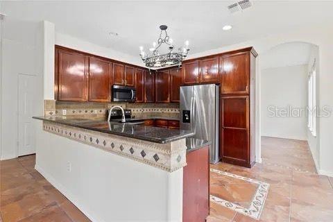 kitchen with a peninsula, tasteful backsplash, pendant lighting, and stainless steel appliances