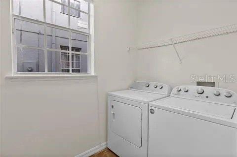 clothes washing area with laundry area, separate washer and dryer, and baseboards