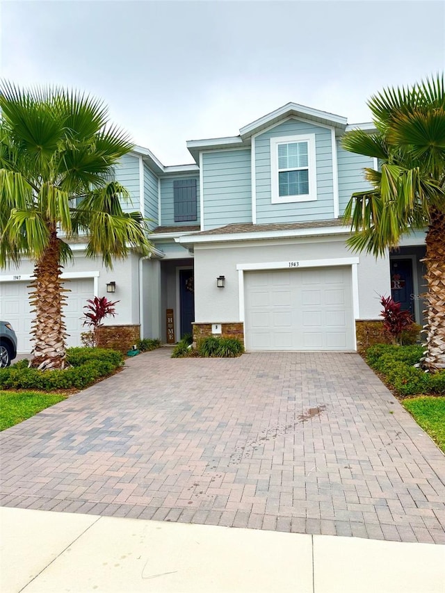 view of front of property with an attached garage, decorative driveway, and stucco siding