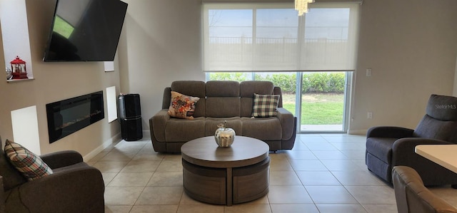 living area with light tile patterned floors, baseboards, and a glass covered fireplace