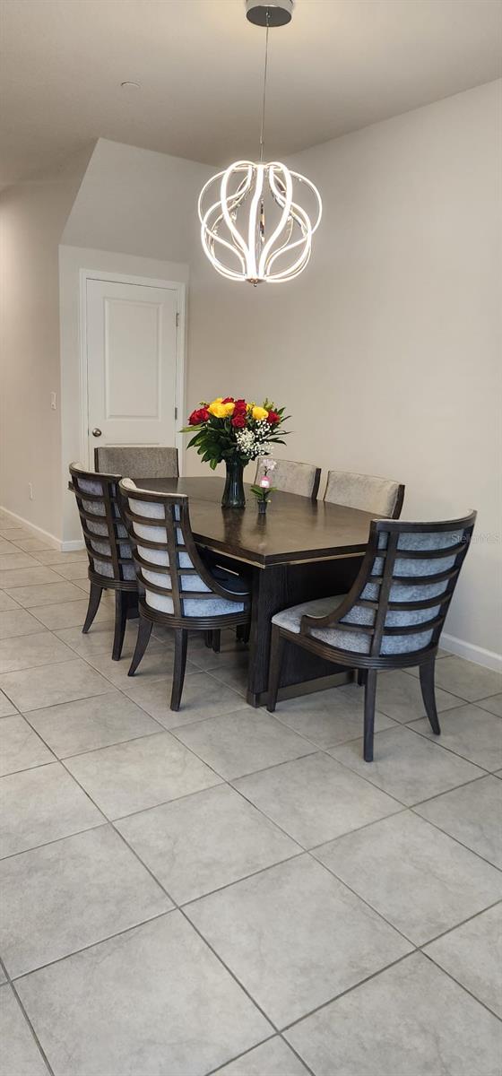 dining area with a chandelier, baseboards, and light tile patterned floors