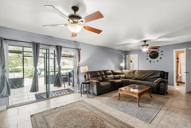 tiled living area with a ceiling fan, a textured ceiling, and baseboards