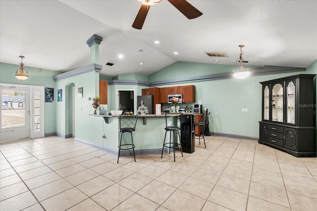 kitchen featuring arched walkways, lofted ceiling, a breakfast bar, stainless steel appliances, and light tile patterned flooring