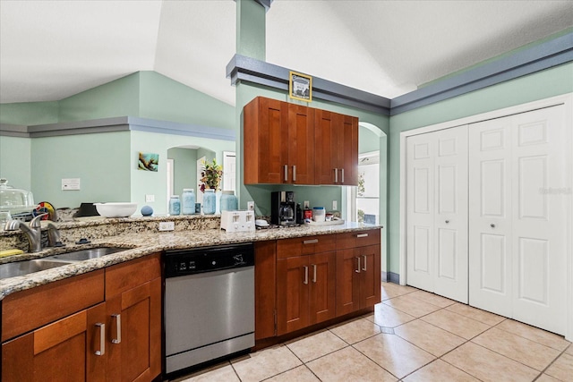 kitchen with arched walkways, dishwasher, vaulted ceiling, a sink, and light tile patterned flooring