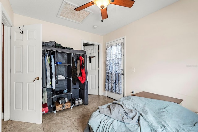 tiled bedroom with attic access, ceiling fan, and a closet