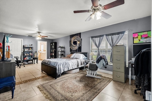 bedroom featuring light tile patterned floors, ensuite bath, a ceiling fan, and baseboards