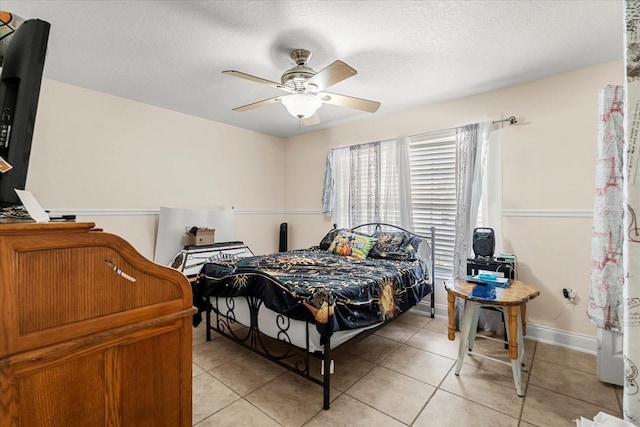 bedroom featuring a textured ceiling, light tile patterned floors, and a ceiling fan