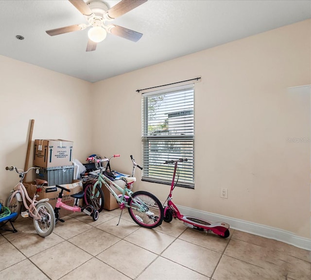 game room with light tile patterned flooring, a ceiling fan, and baseboards