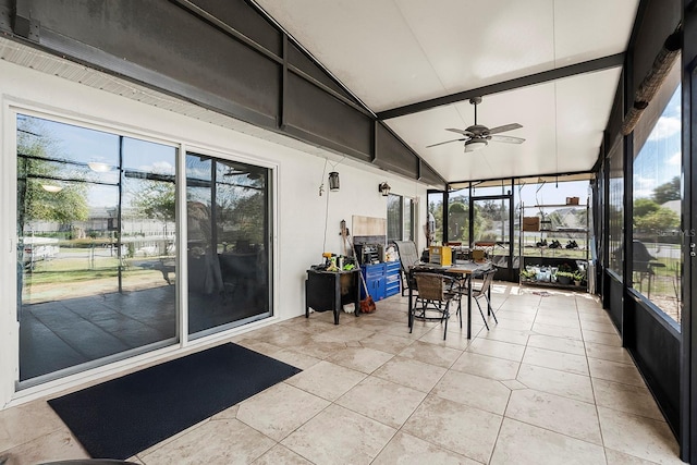 sunroom with vaulted ceiling with beams, a wealth of natural light, and a ceiling fan