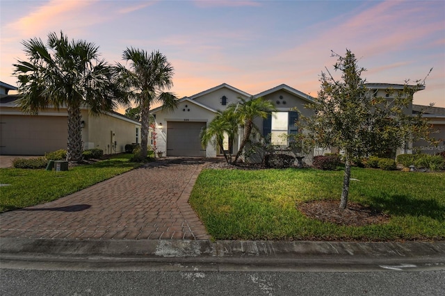 view of front facade featuring an attached garage, stucco siding, decorative driveway, and a front yard