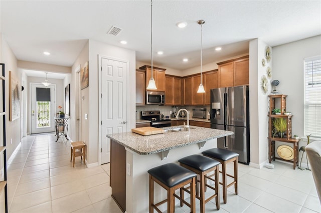 kitchen featuring stainless steel appliances, a sink, visible vents, light stone countertops, and tasteful backsplash