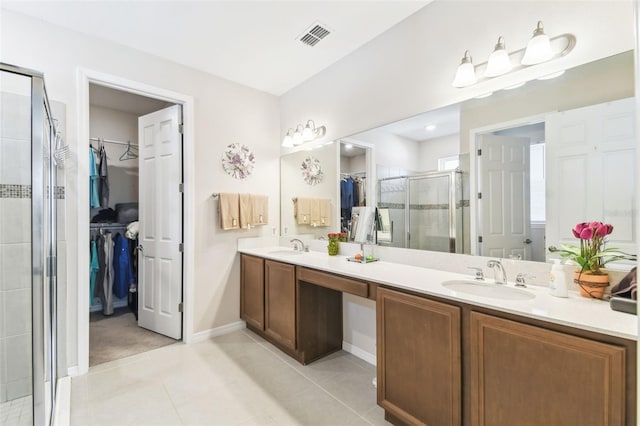 full bath featuring a stall shower, a sink, visible vents, and a walk in closet