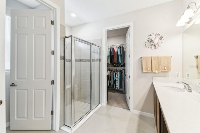 full bathroom with a stall shower, baseboards, tile patterned floors, a spacious closet, and vanity