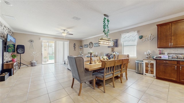 dining area featuring light tile patterned floors, a textured ceiling, and crown molding