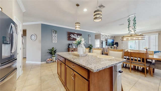 kitchen featuring light stone counters, a center island, brown cabinets, ornamental molding, and stainless steel fridge with ice dispenser