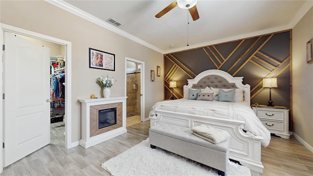 bedroom with a walk in closet, crown molding, a closet, visible vents, and light wood-type flooring