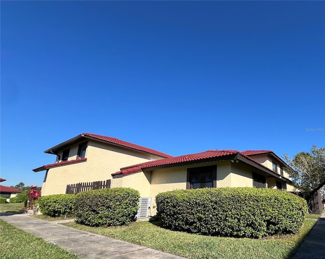 view of home's exterior with a tiled roof, central AC unit, and stucco siding