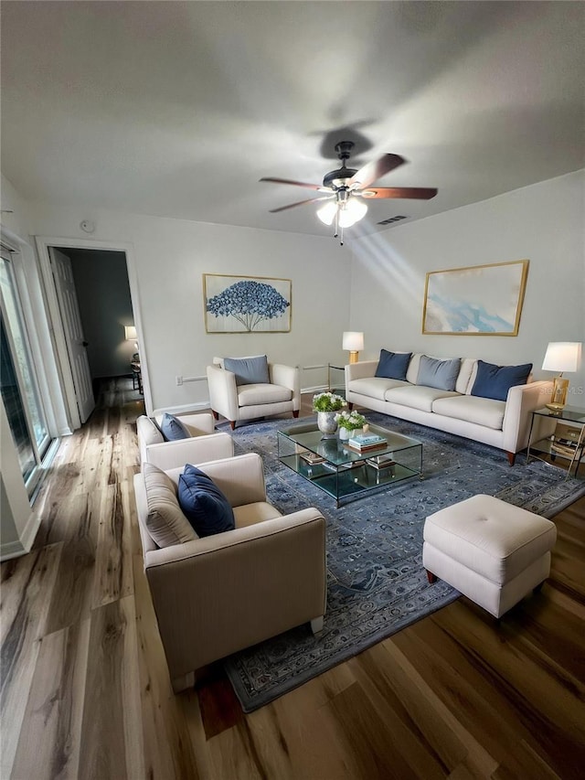 living room featuring wood finished floors, visible vents, and a ceiling fan