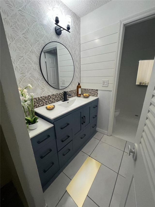 bathroom featuring wallpapered walls, toilet, tile patterned floors, a textured ceiling, and vanity