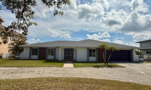 ranch-style home with a garage, fence, driveway, stucco siding, and a front lawn