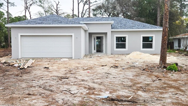 ranch-style home with a garage, roof with shingles, and stucco siding