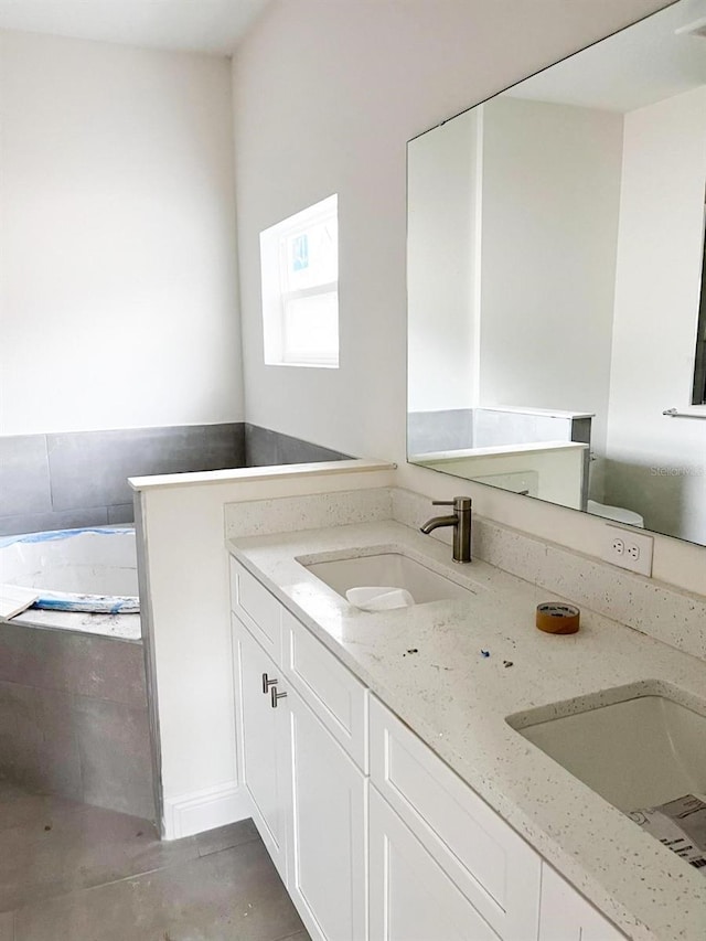 full bath featuring a garden tub, a sink, and double vanity