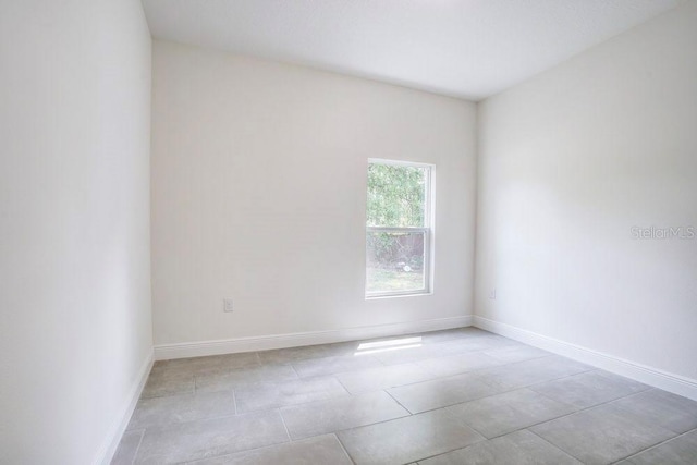 spare room with baseboards and light tile patterned floors