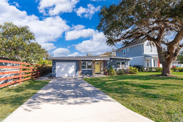 view of front of property featuring an attached garage, fence, a front lawn, and decorative driveway