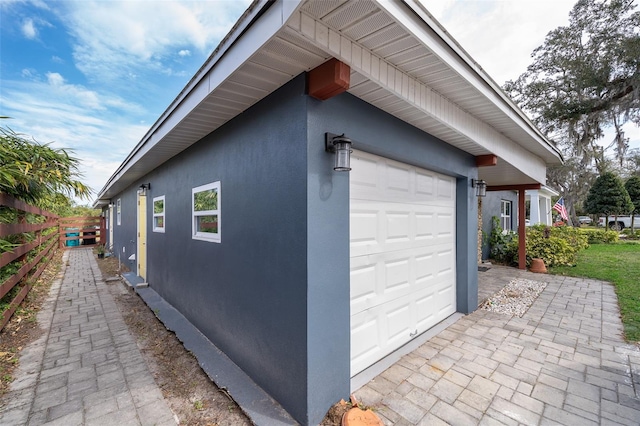 view of property exterior featuring a garage, fence, and stucco siding