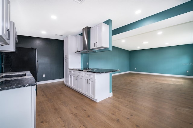 kitchen with dark wood-style floors, white cabinets, wall chimney range hood, baseboards, and black electric cooktop