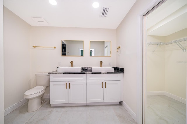 bathroom featuring a walk in closet, visible vents, a sink, and toilet