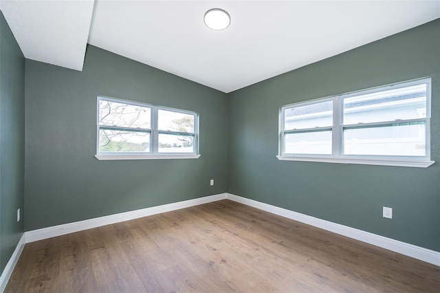 unfurnished room with lofted ceiling, wood finished floors, and baseboards