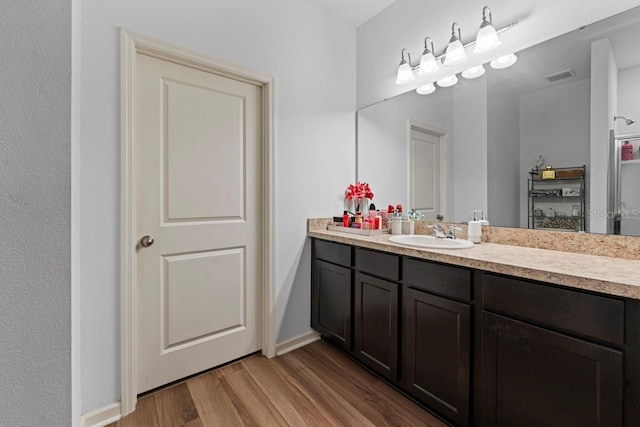 bathroom featuring visible vents, vanity, baseboards, and wood finished floors