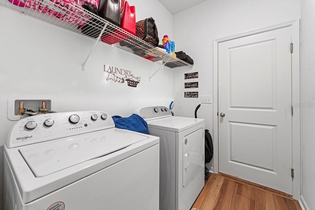 clothes washing area featuring laundry area, washer and clothes dryer, and light wood-type flooring