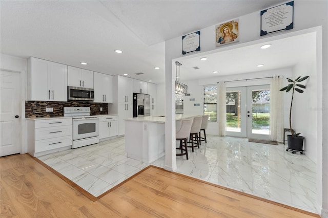 kitchen with white cabinets, marble finish floor, appliances with stainless steel finishes, french doors, and backsplash