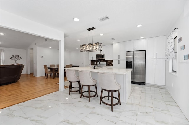 kitchen featuring light countertops, visible vents, appliances with stainless steel finishes, white cabinets, and a sink