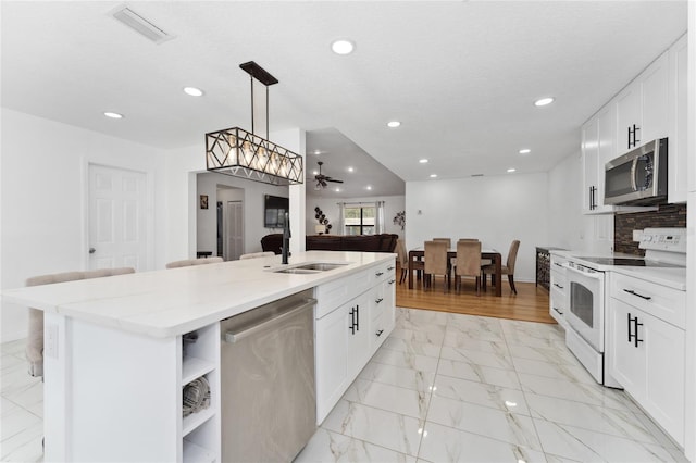 kitchen featuring visible vents, marble finish floor, appliances with stainless steel finishes, open shelves, and a center island with sink