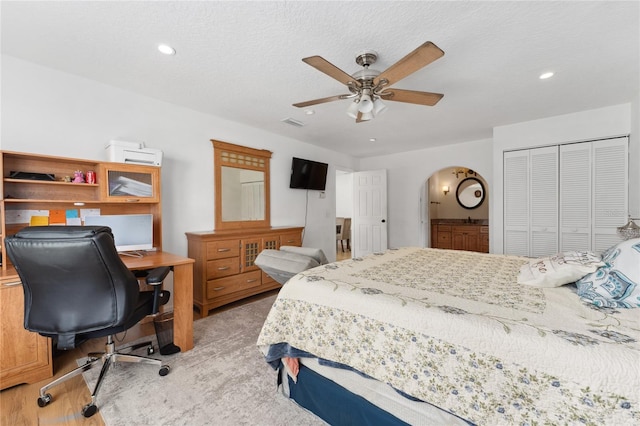 bedroom with arched walkways, ceiling fan, a textured ceiling, recessed lighting, and a closet