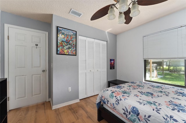 bedroom featuring visible vents, ceiling fan, wood finished floors, a textured ceiling, and a closet