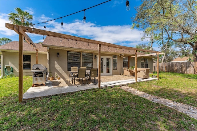 rear view of property featuring a patio, fence, a yard, french doors, and stucco siding