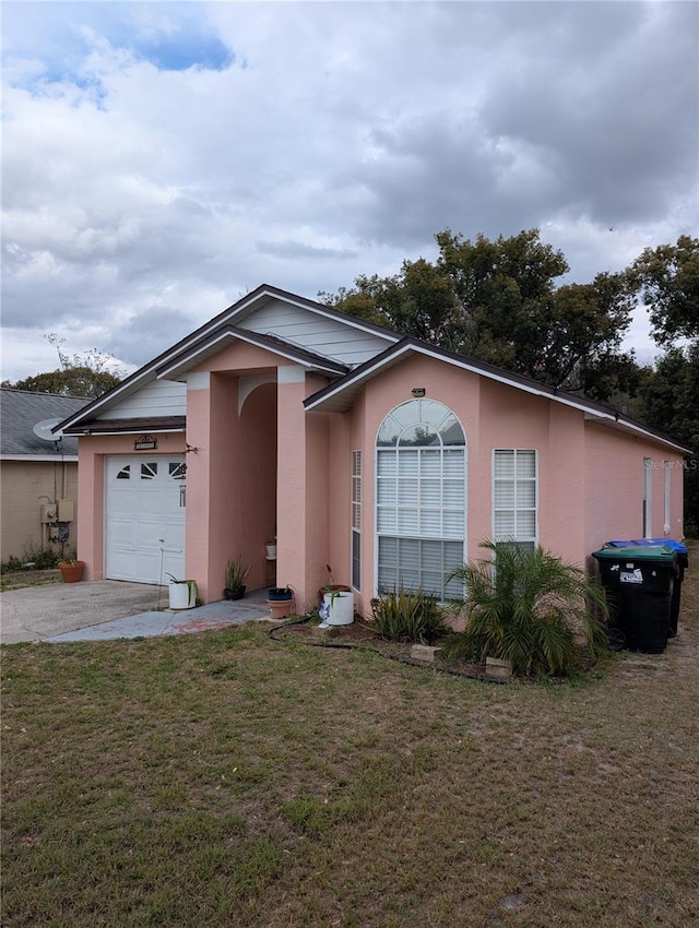 single story home featuring concrete driveway, an attached garage, a front lawn, and stucco siding