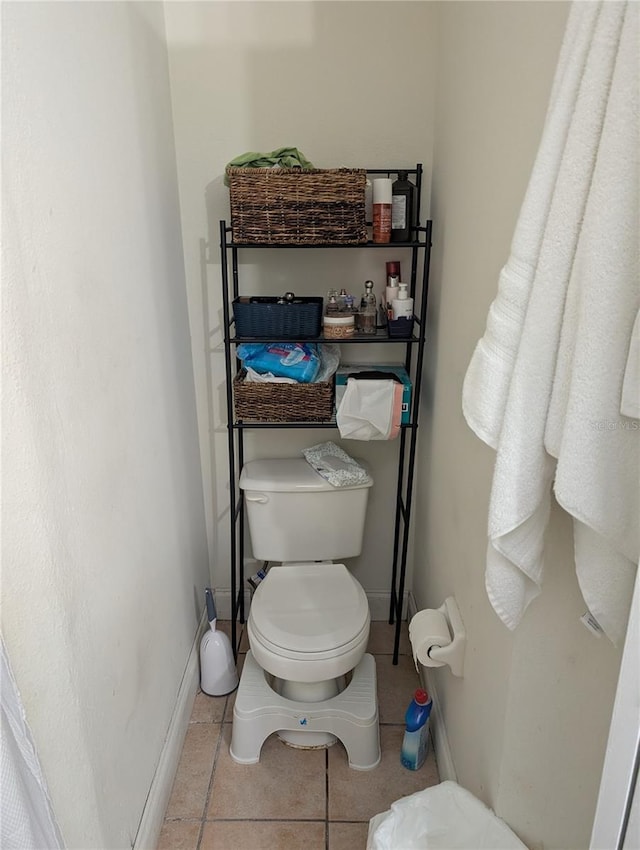 bathroom with tile patterned flooring, baseboards, and toilet