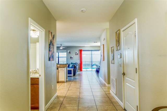 corridor with visible vents, baseboards, and light tile patterned floors