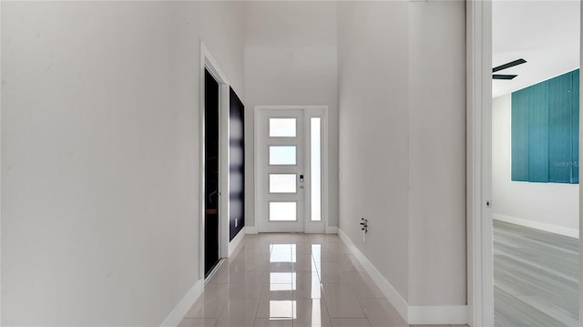 interior space with light tile patterned floors, a high ceiling, and baseboards