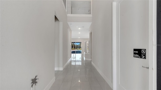 corridor featuring light tile patterned floors, visible vents, and baseboards