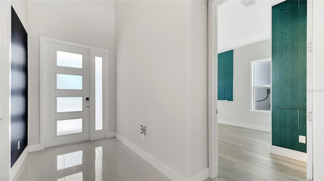 foyer entrance featuring a high ceiling, baseboards, visible vents, and light wood-type flooring