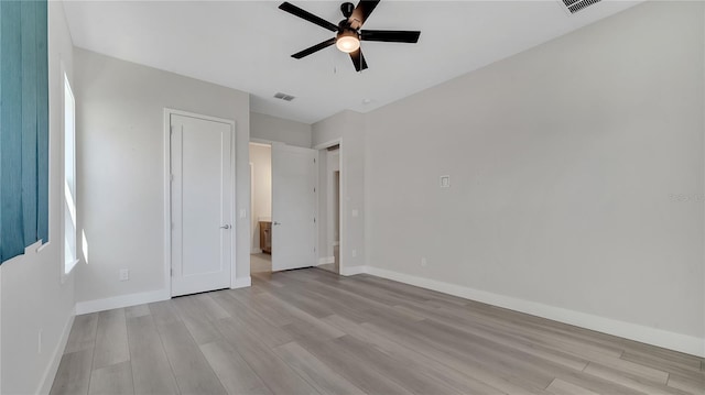 unfurnished bedroom featuring a ceiling fan, baseboards, visible vents, and light wood-type flooring