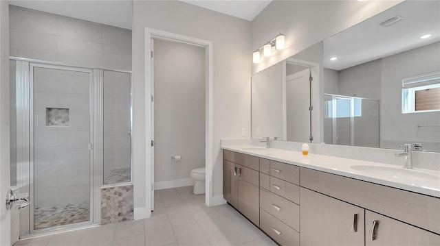 full bathroom featuring double vanity, a shower stall, toilet, and a sink