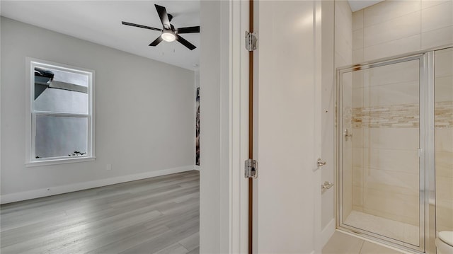 full bathroom featuring a shower stall, baseboards, ceiling fan, and wood finished floors