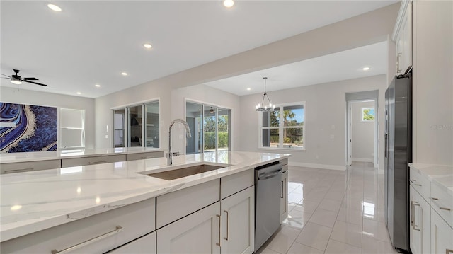 kitchen with a sink, light stone counters, appliances with stainless steel finishes, and recessed lighting